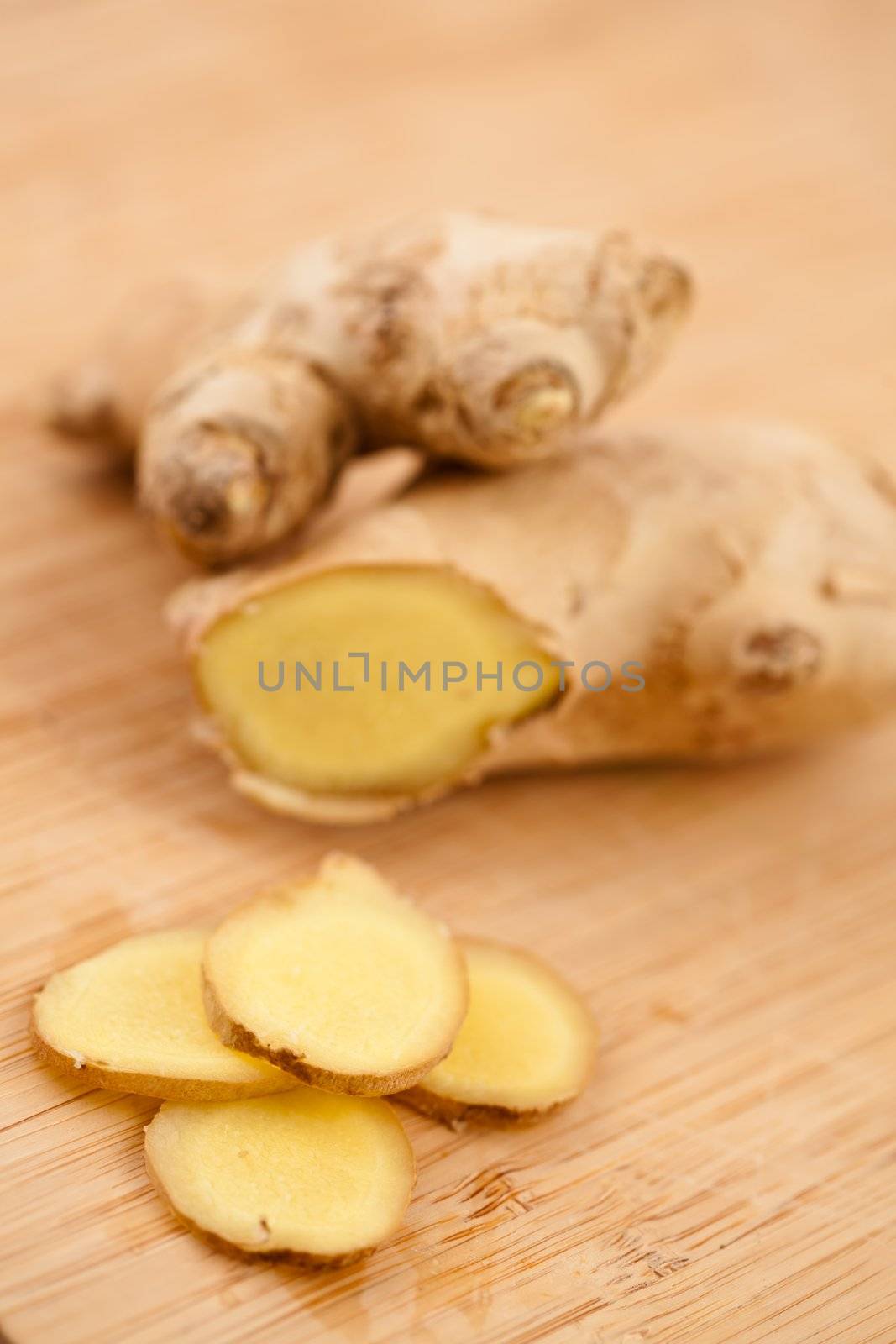 Slice of ginger and blurred piece of ginger on a worktop