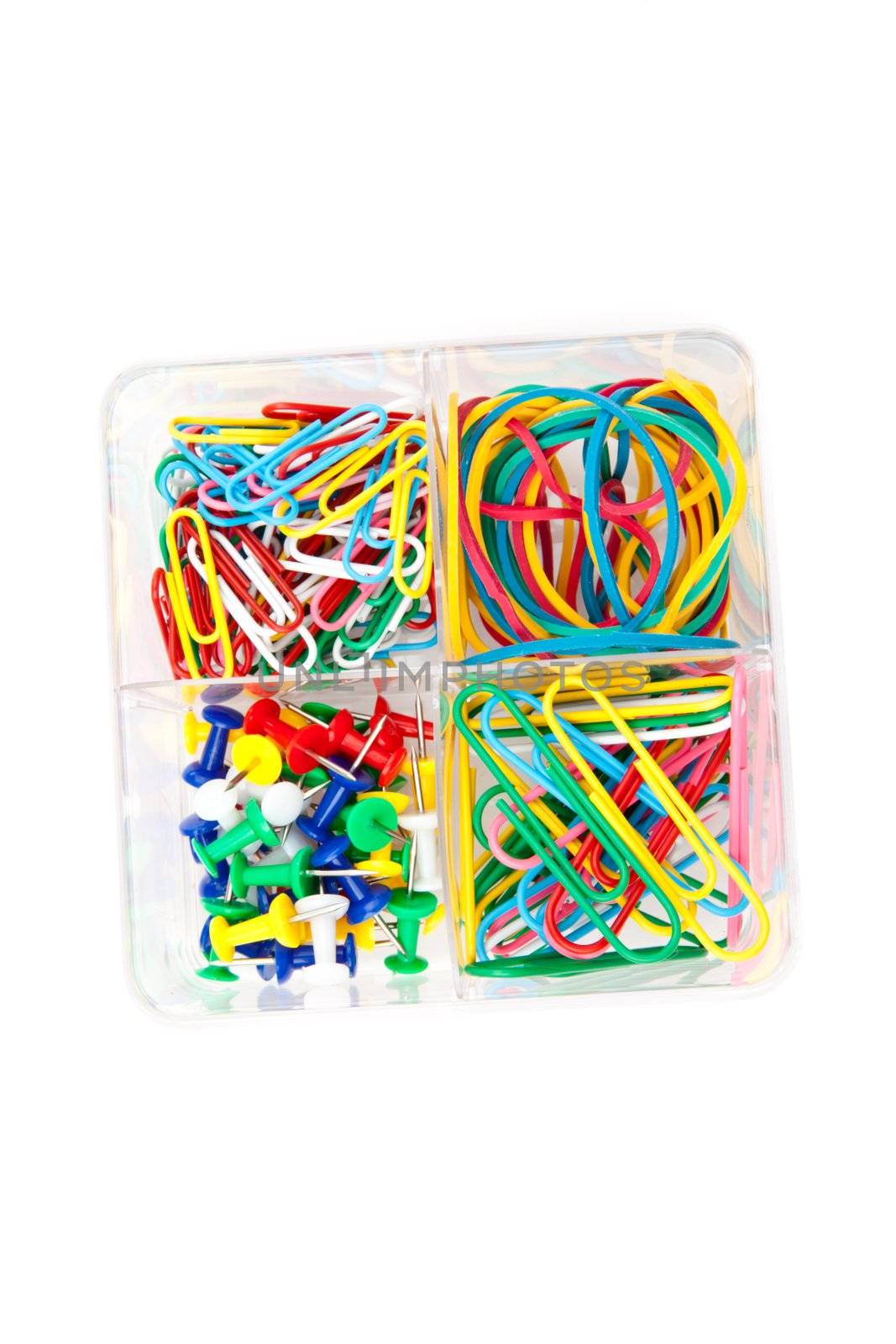 Box of multicolored of pushpins paperclips and elastics against a white background