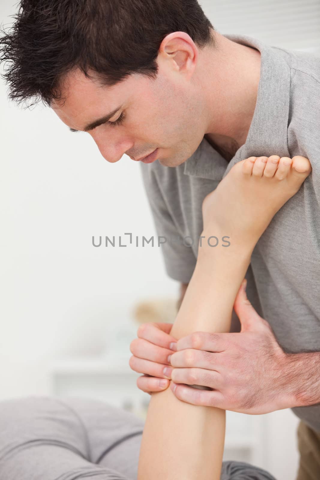 Woman lying while a physiotherapist is manipulating her leg indoors