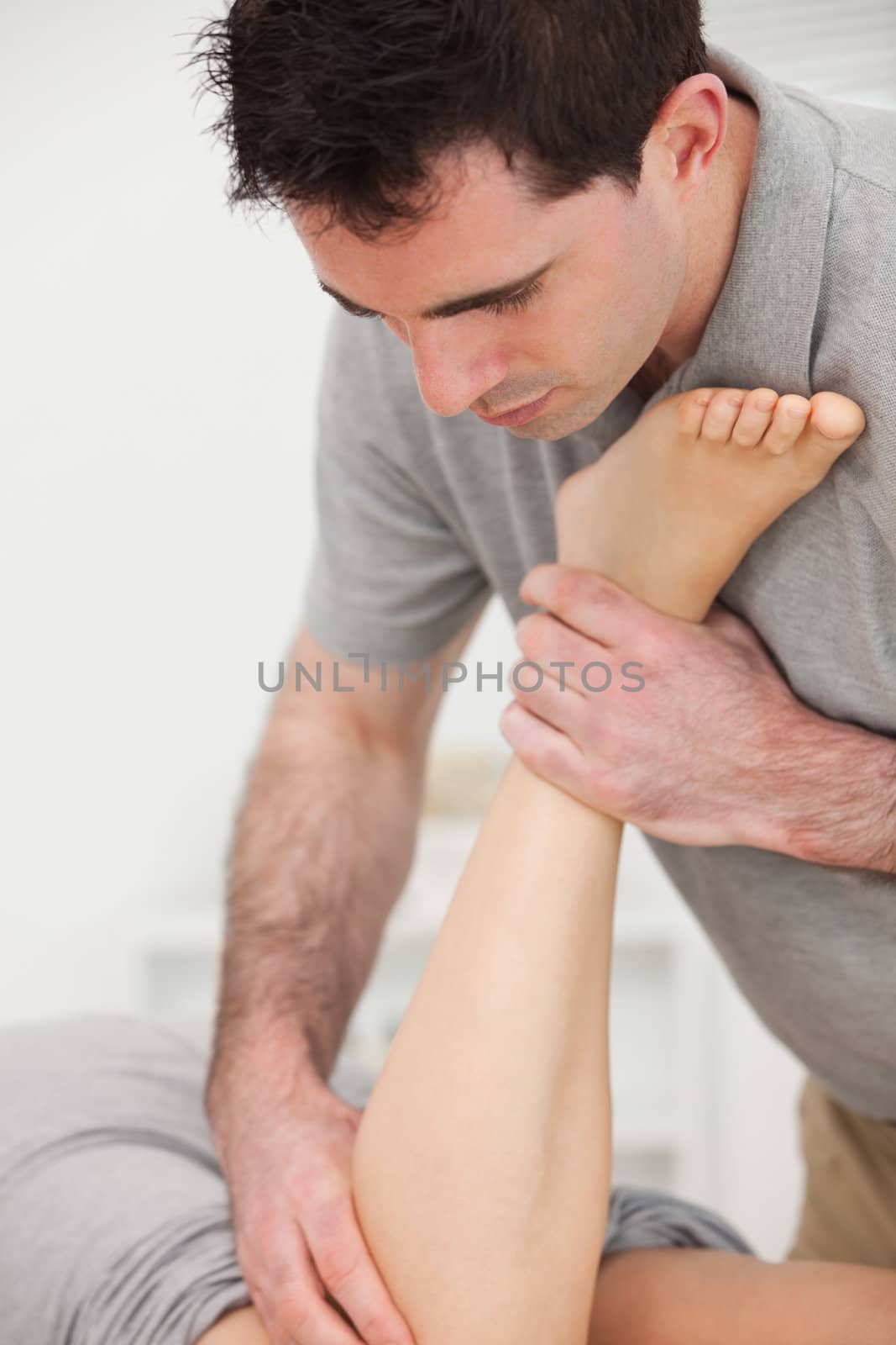 Physiotherapist manipulating the leg of a woman while she is lying in a room