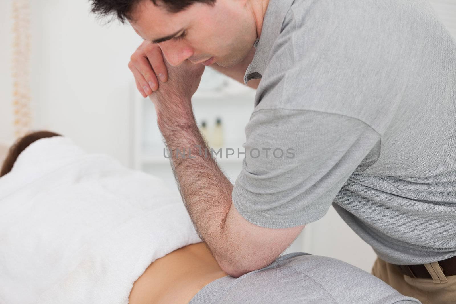 Woman lying forward while a physiotherapist is massaging her back in a physio room