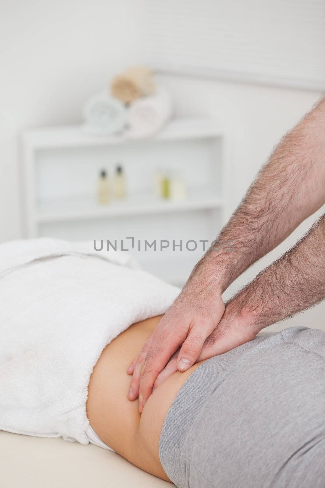 Woman lying while a physiotherapist massing her back in a physio room