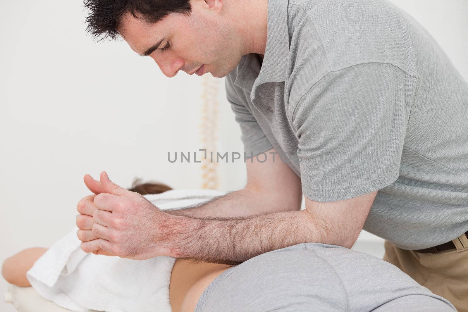 Physiotherapist massaging the back of a patient with his forearms in a room