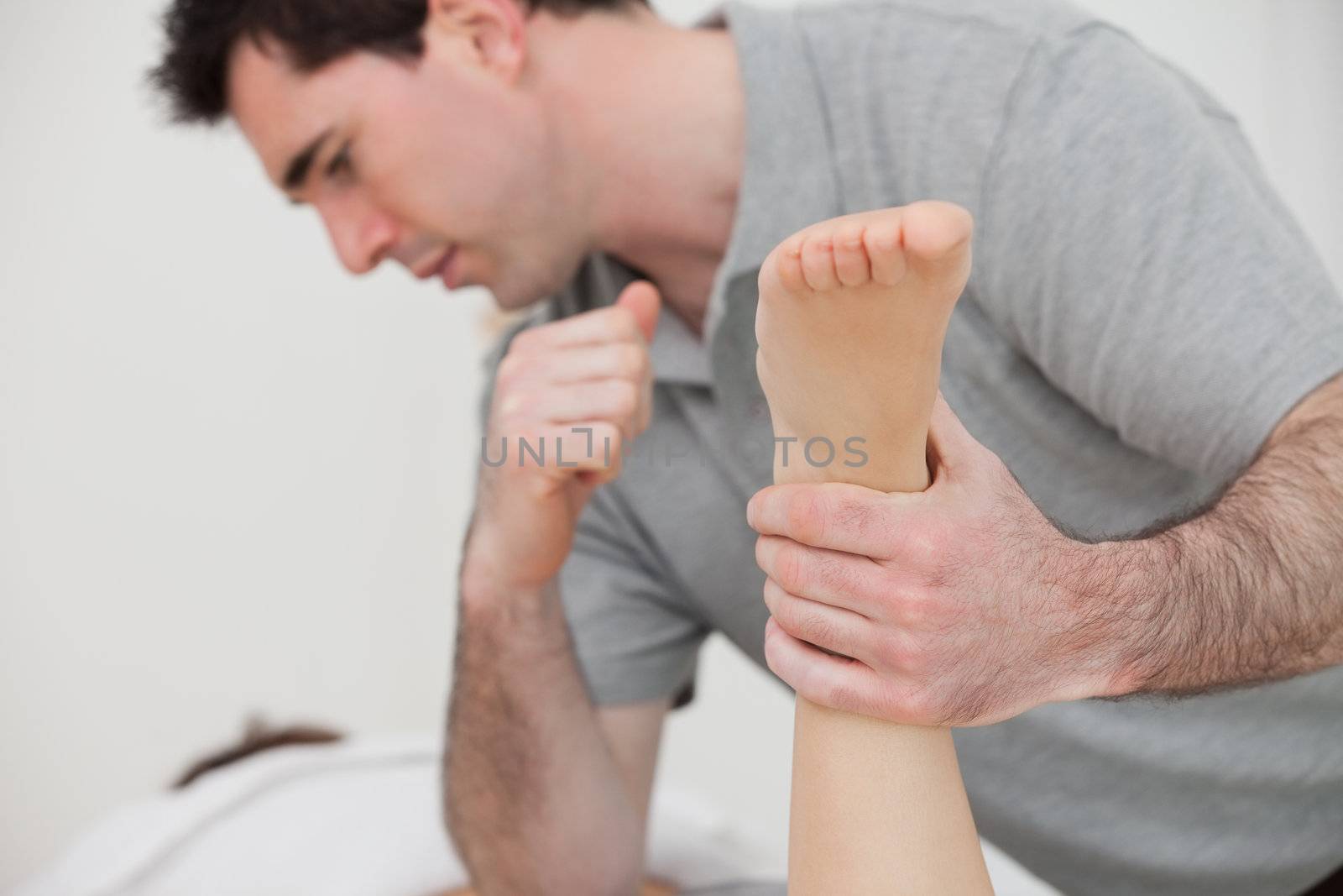 Physio manipulating the leg of a patient by Wavebreakmedia