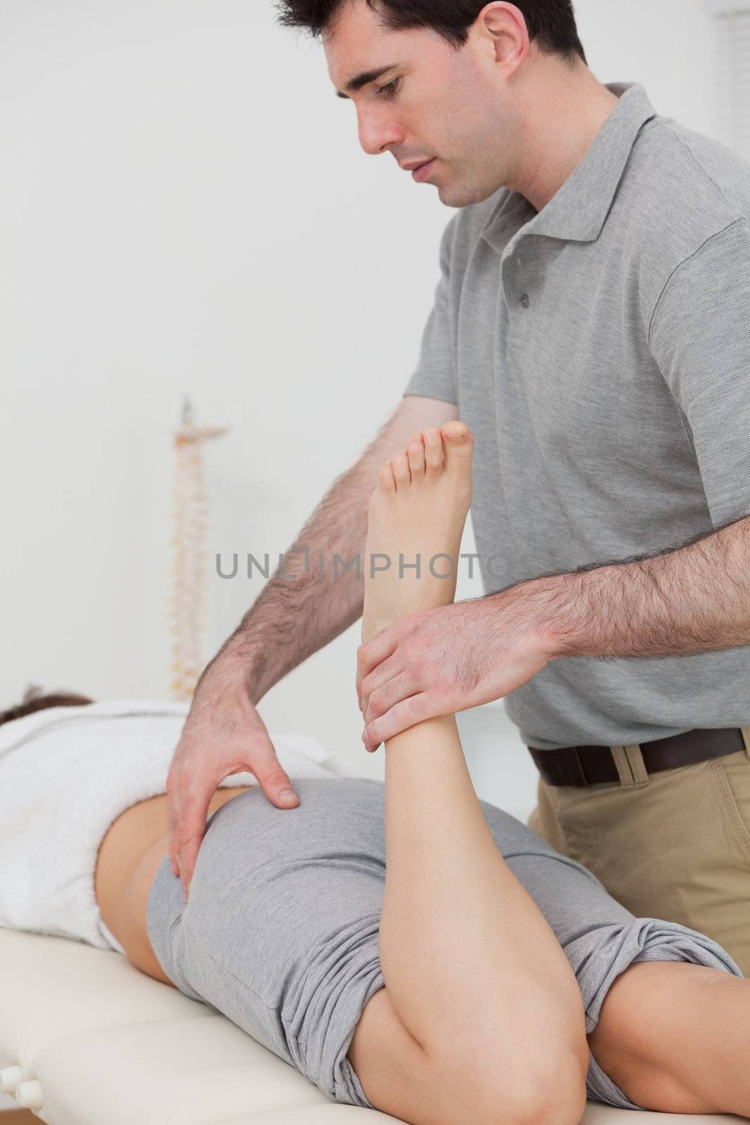 Woman lying while a physiotherapist is bending her leg in a room