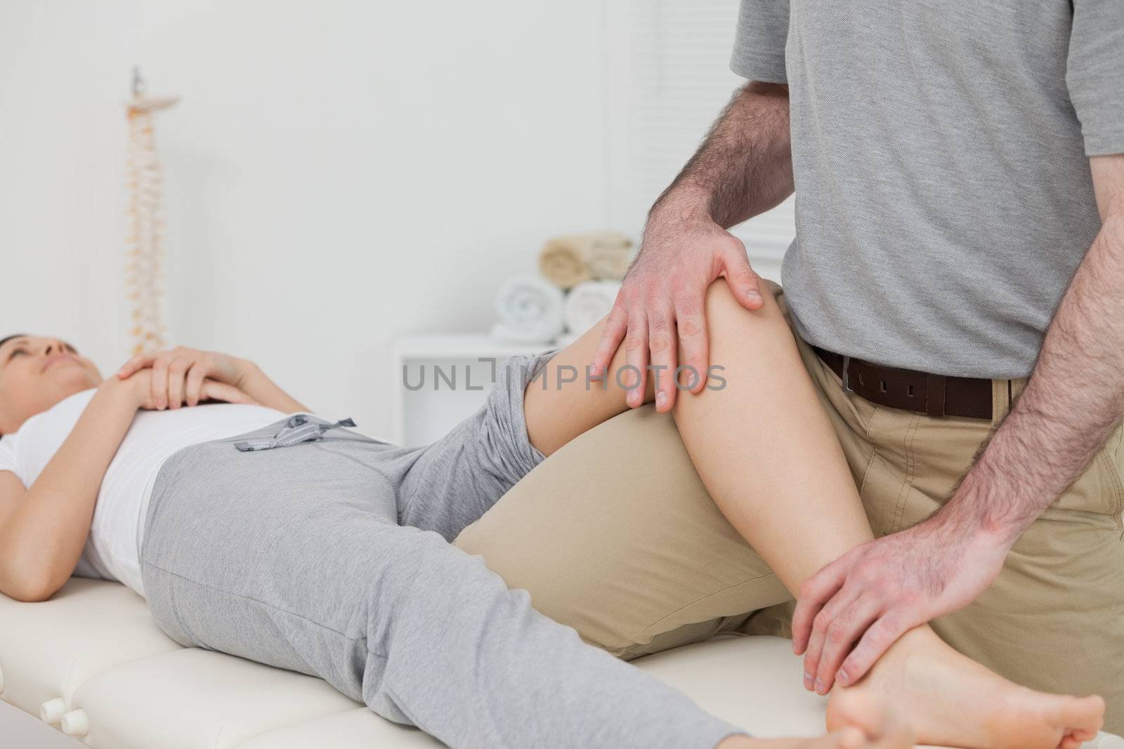 Woman lying on her back while a physiotherapist manipulates her leg in a physio room