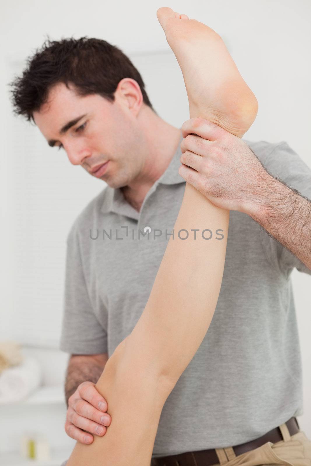 Chiropractor extending the leg of a patient in a room