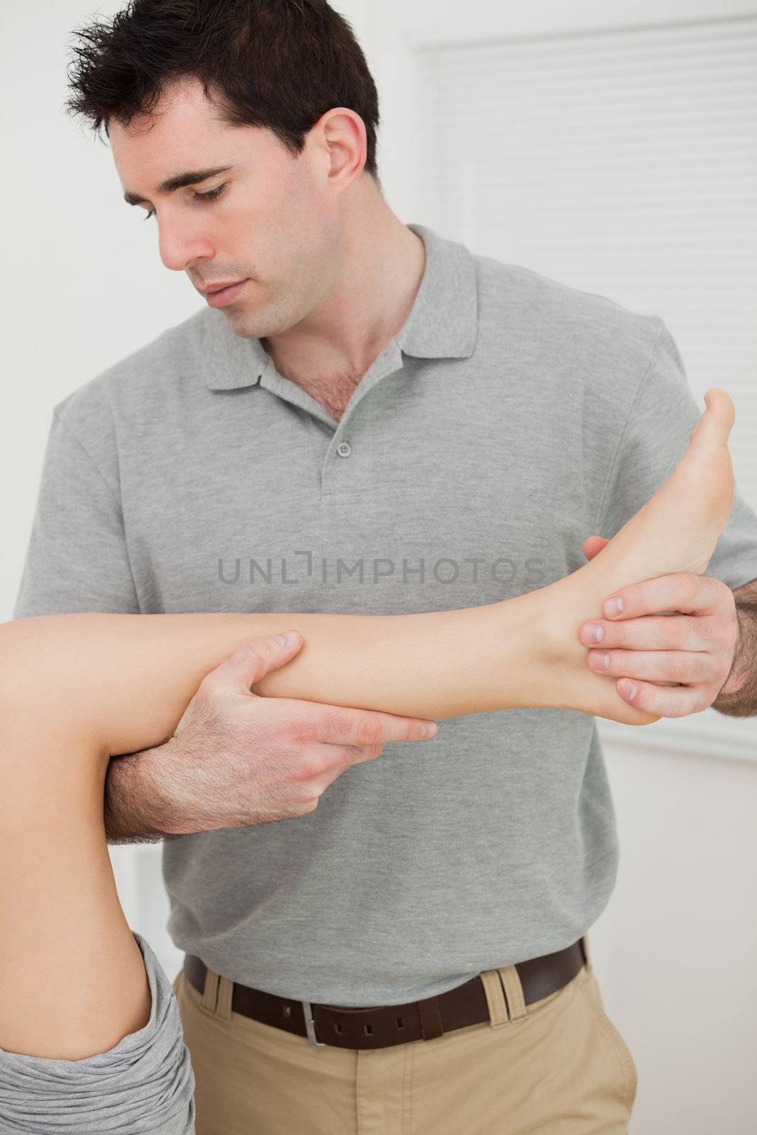 Physio folding the leg of a patient by Wavebreakmedia