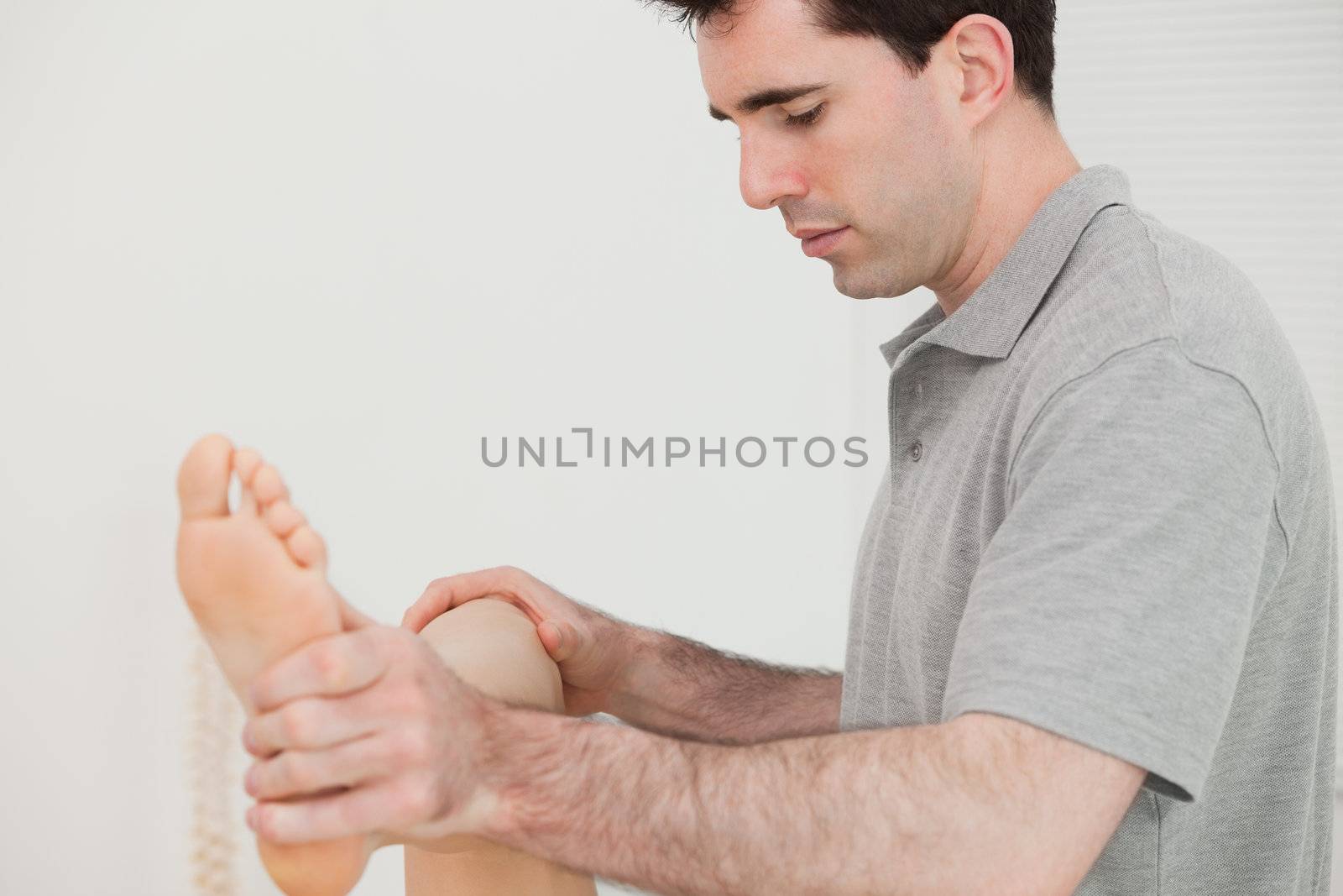 Physio moving his the leg of his patient in a room