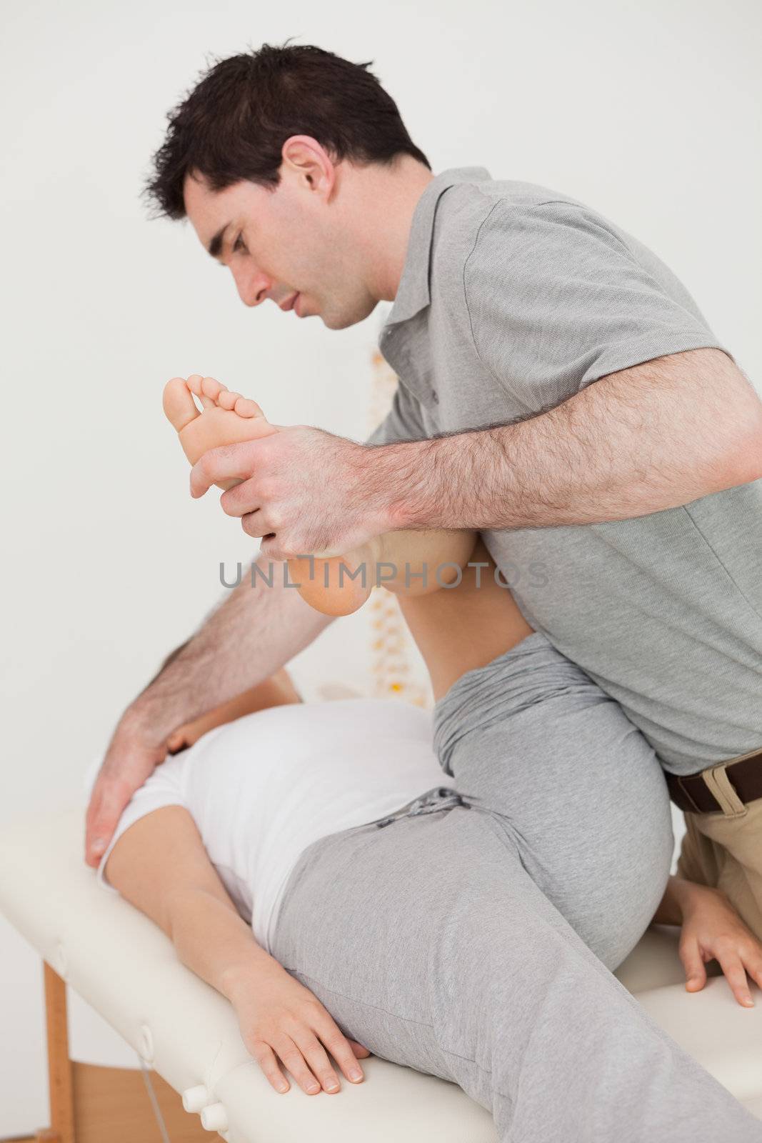 Serious osteopath stretching the leg of his patient by Wavebreakmedia