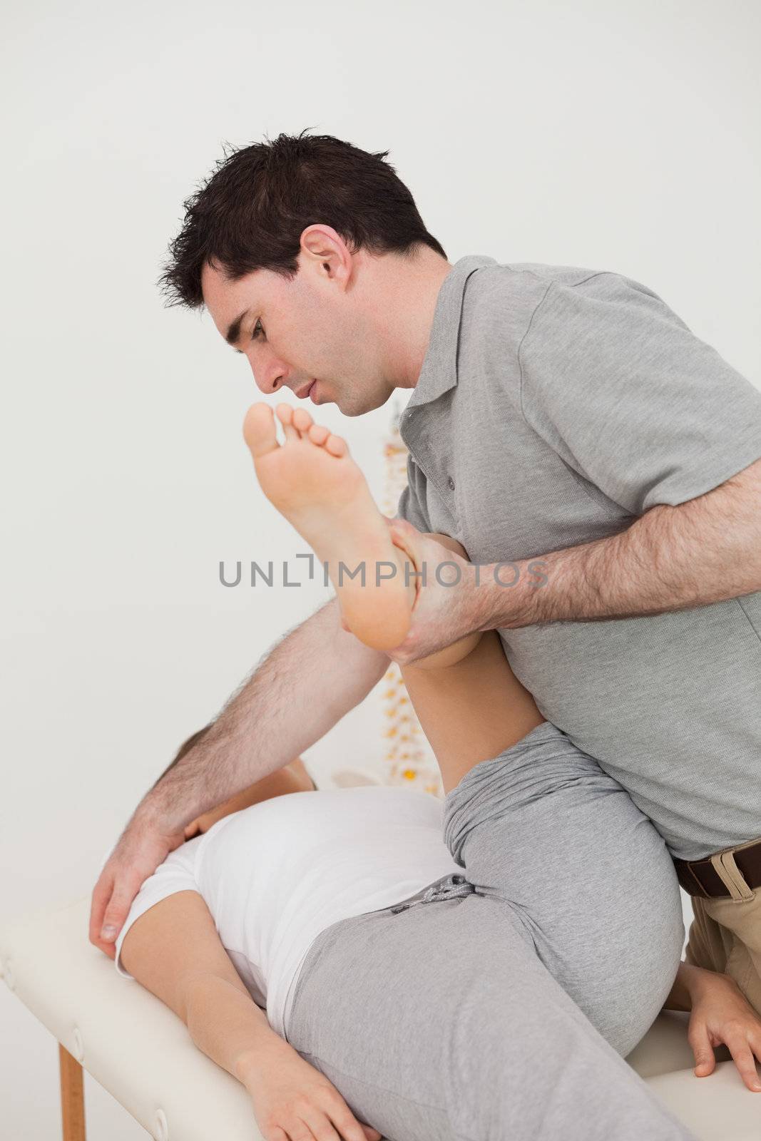 Woman lying while a physio moving her leg in a room