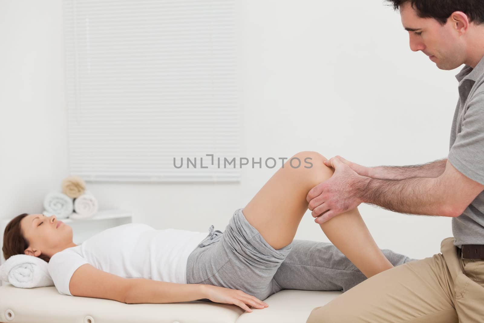 Man massaging the knee of a woman while sitting by Wavebreakmedia