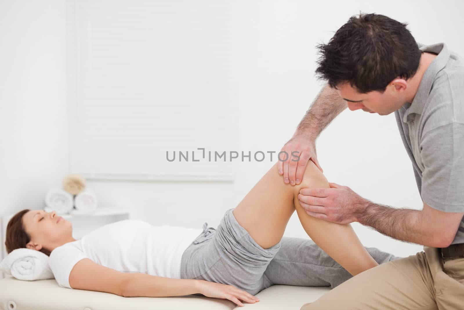 Brown-haired man massaging the knee of a woman in a room