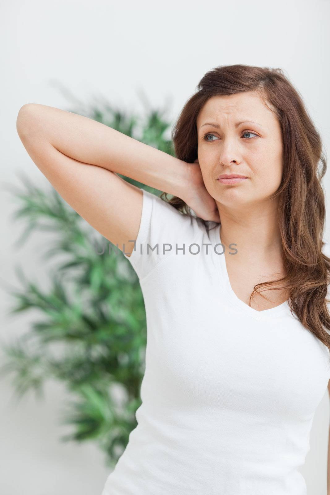 Woman standing while placing her hand on her neck by Wavebreakmedia