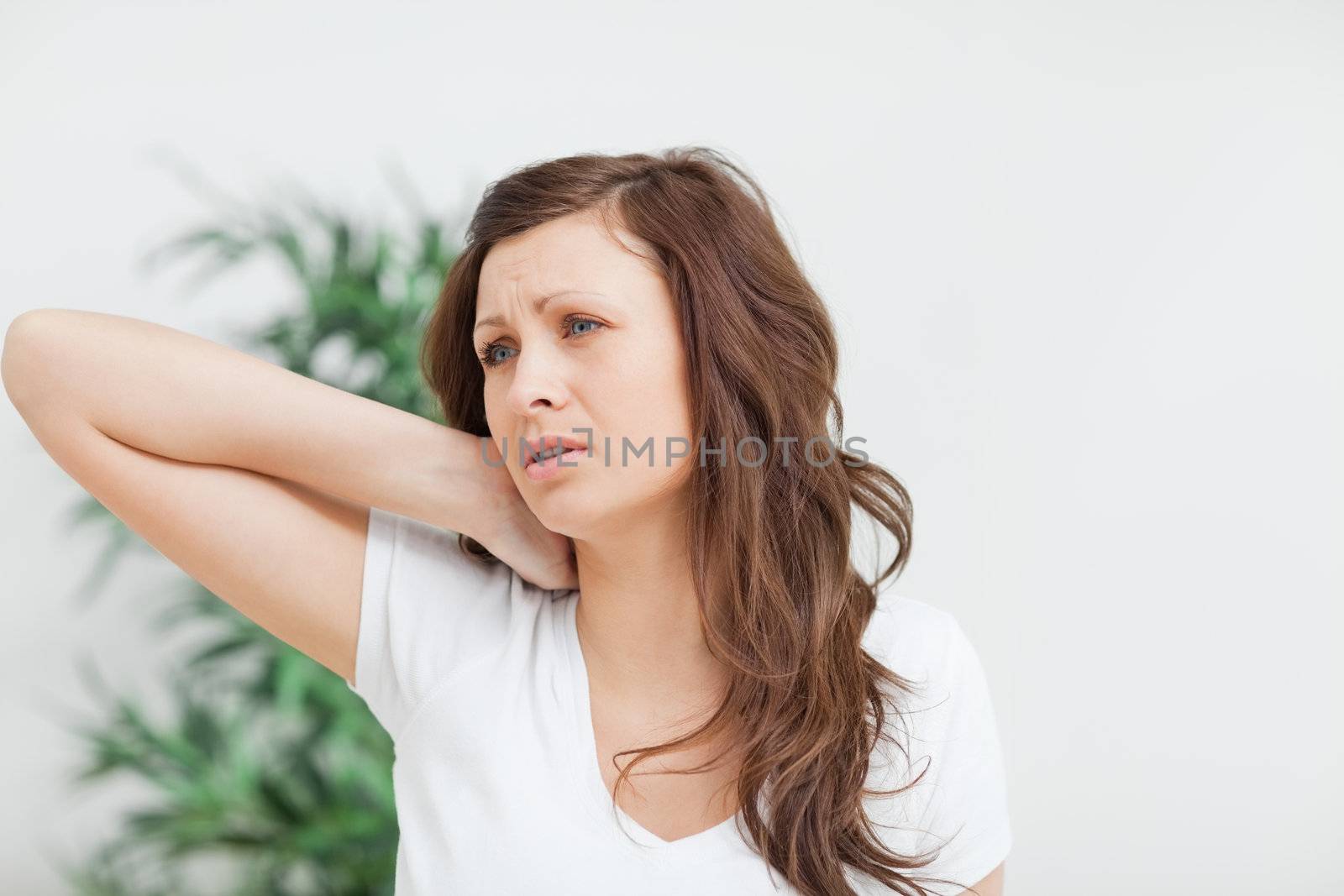 Woman placing her hand on her neck in a room