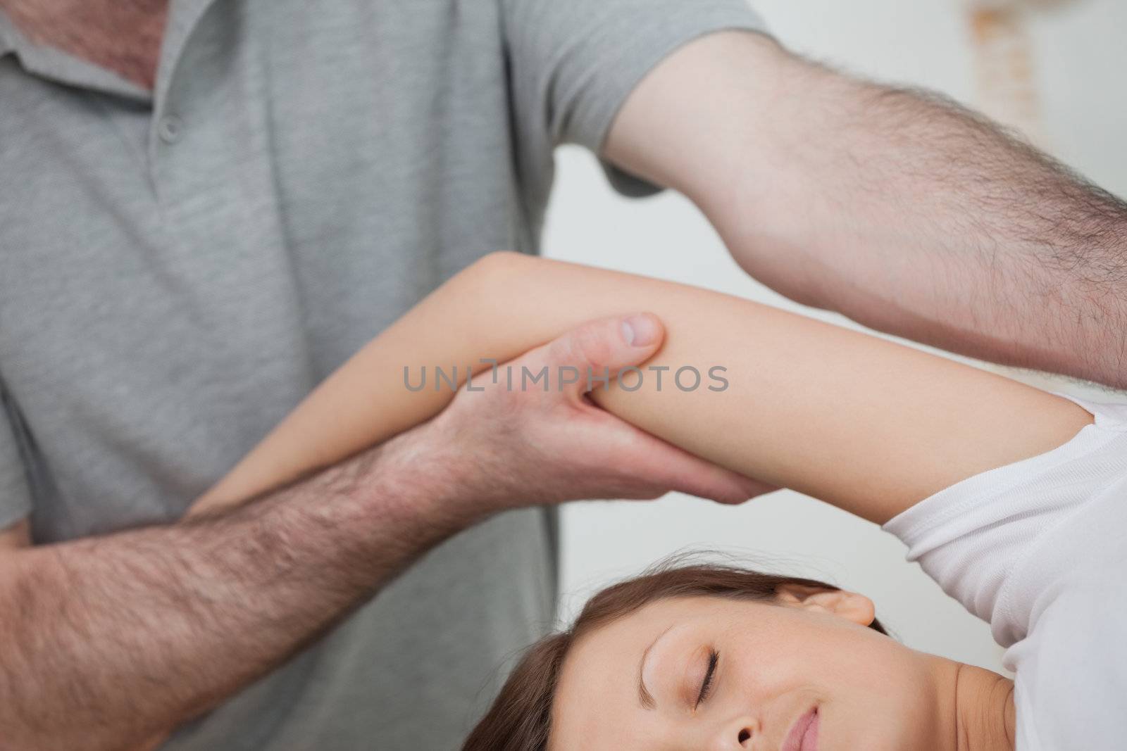 Osteopath holding the arm of a woman while massaging her body in a room