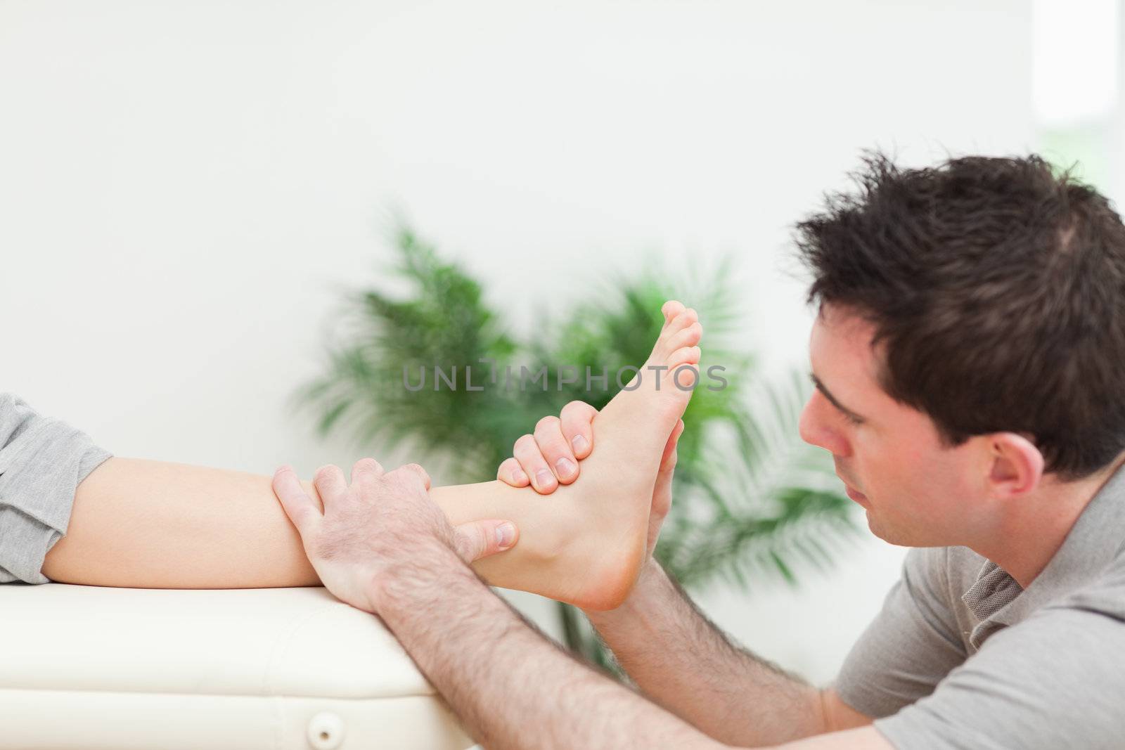 Physiotherapist sitting while massaging a foot in a room