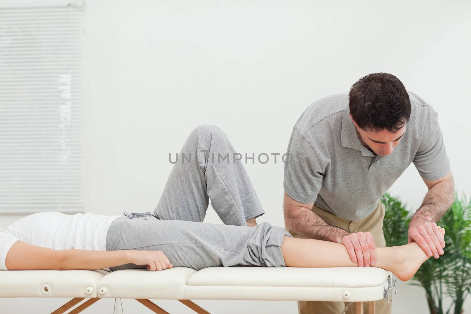 Chiropractor examining the foot of a woman by Wavebreakmedia