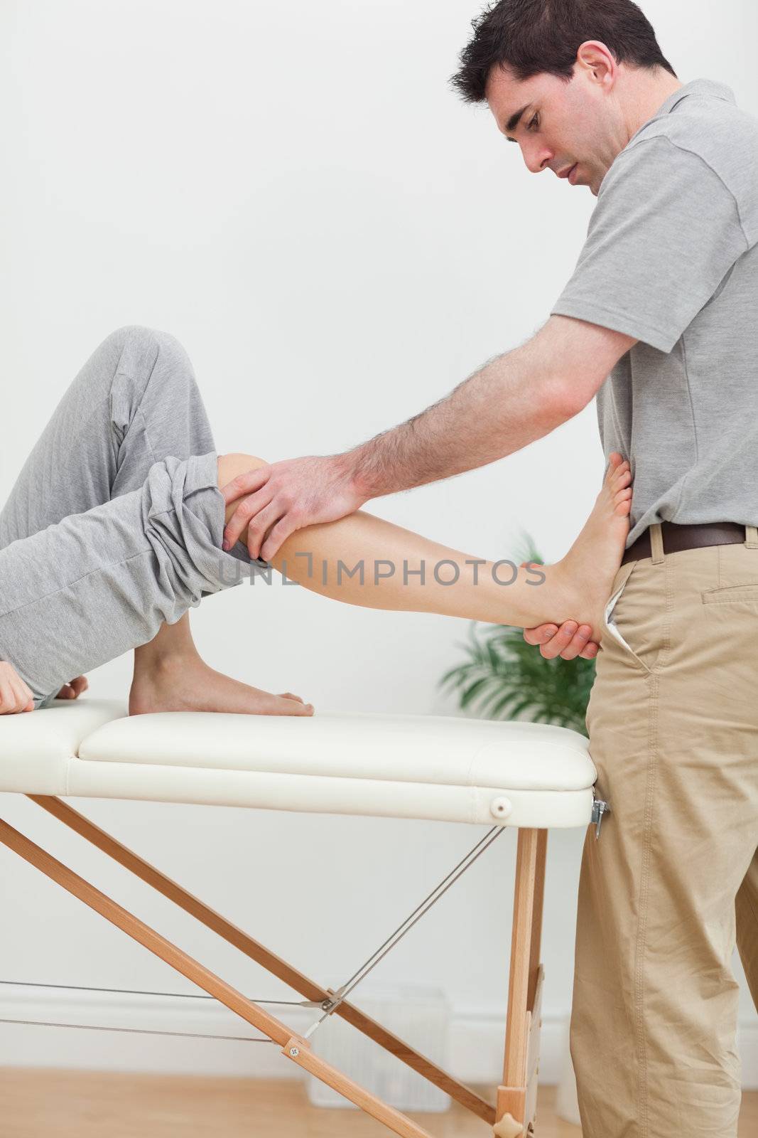 Brunette physiotherapist stretching a foot in a room