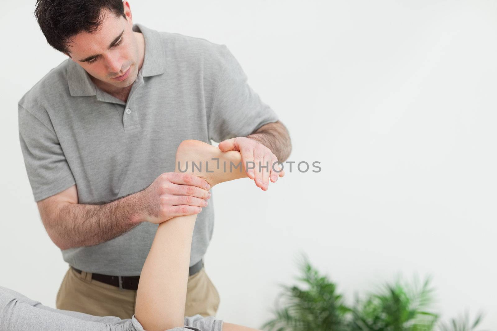 Brown-haired therapist stretching the foot of a patient in a room