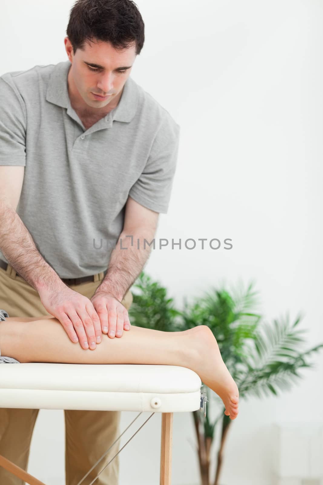 Brunette masseur massaging the leg of a woman in a room