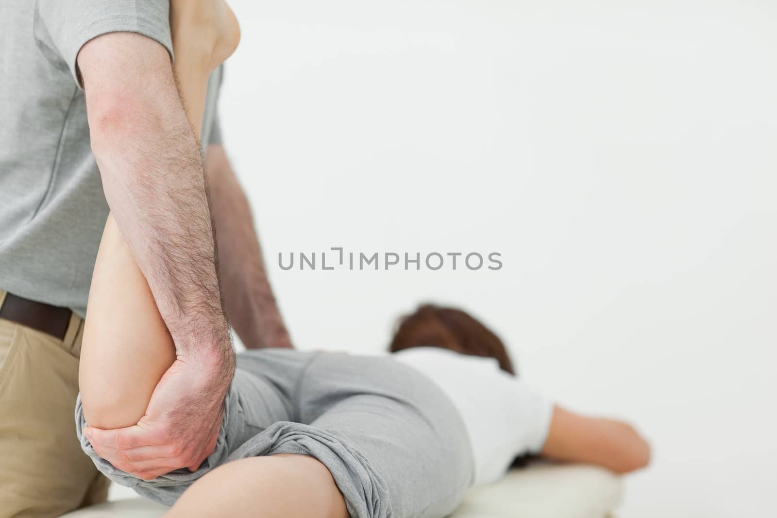 Woman lying forward while a man is stretching her leg in a room