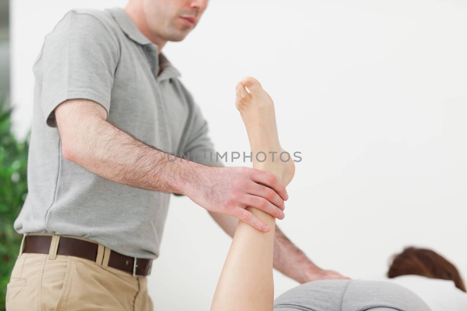 Woman lying while being stretched by a man in a room