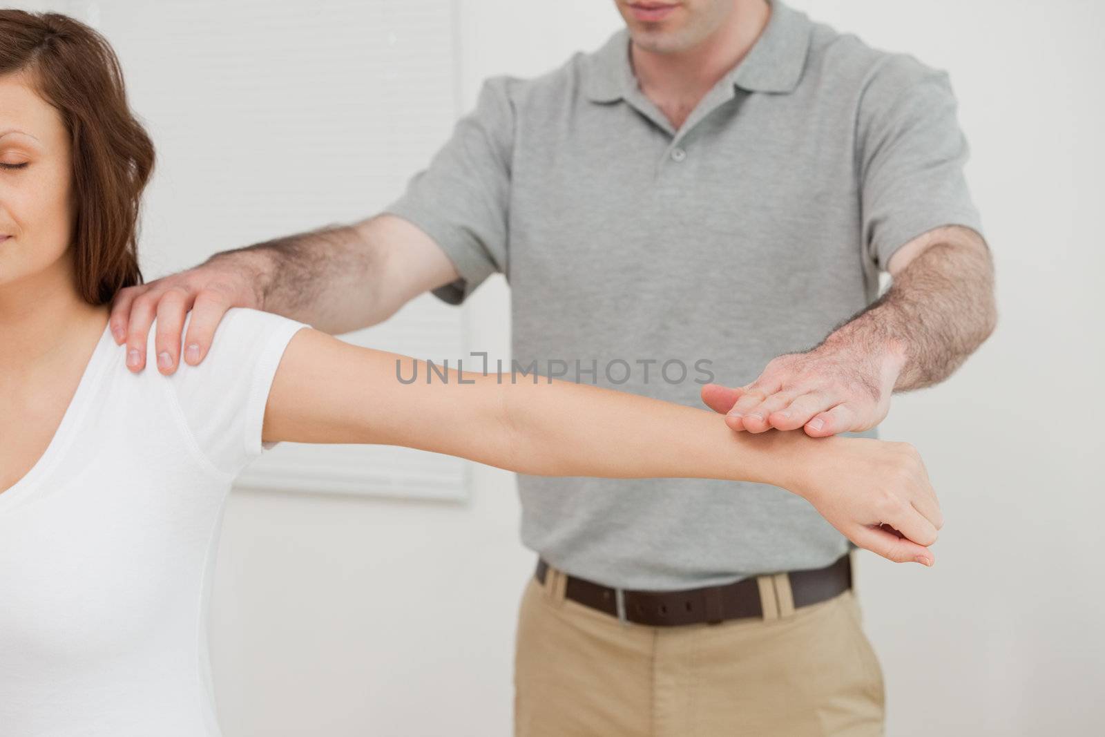 Woman sitting while a doctor is examining her arm by Wavebreakmedia