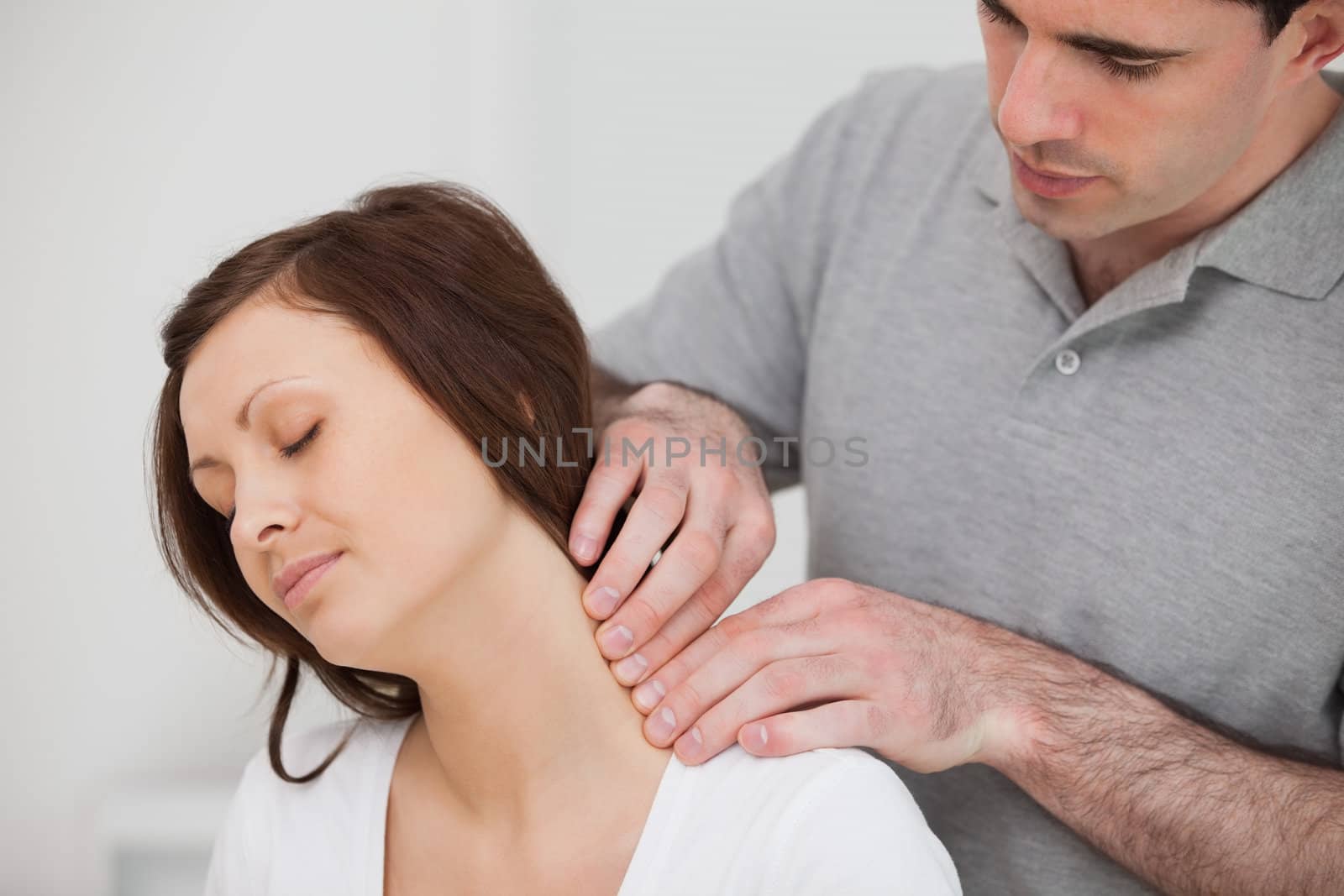 Man massaging the neck of his patient in a medical room