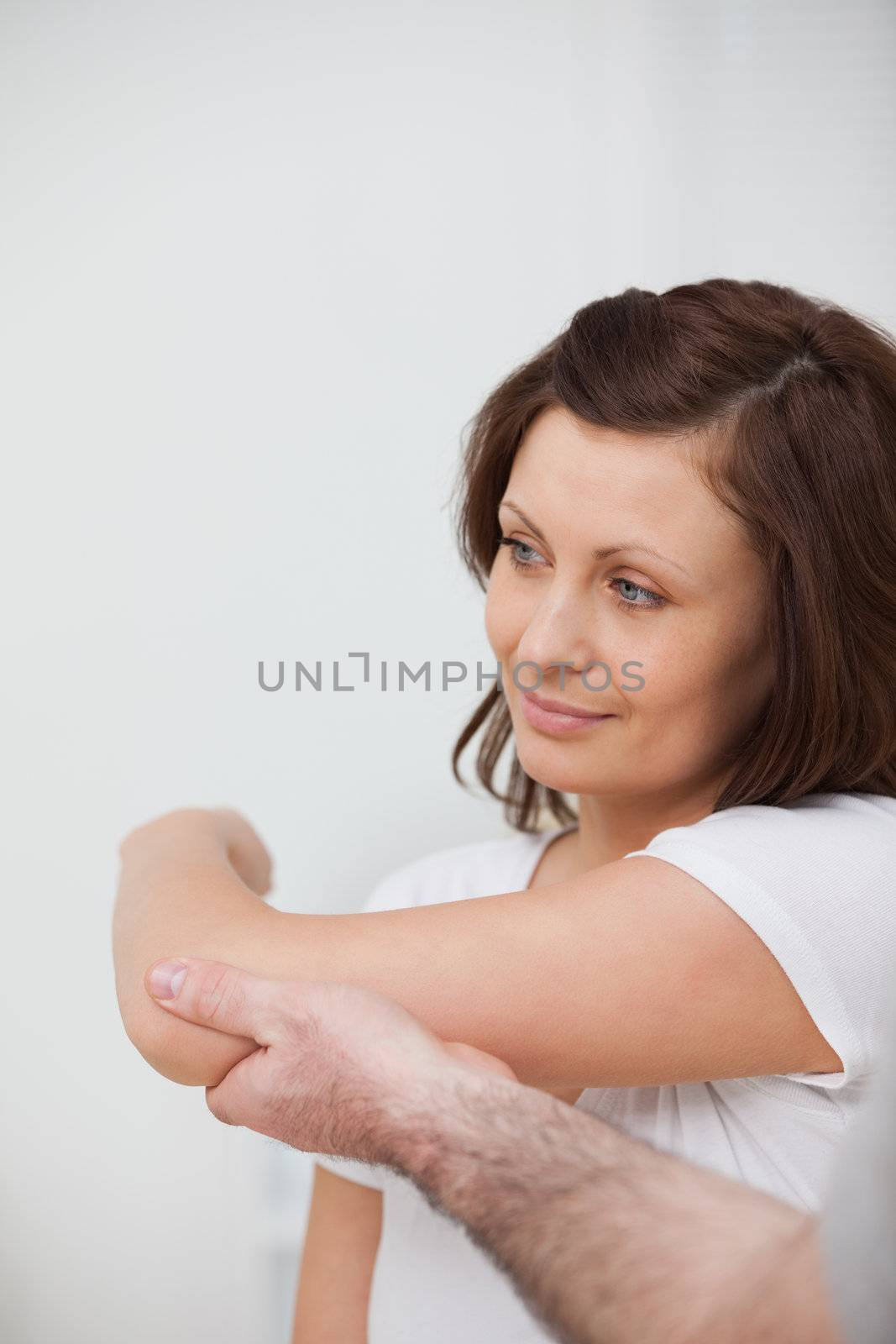 Smiling woman being stretched by a man in against grey background