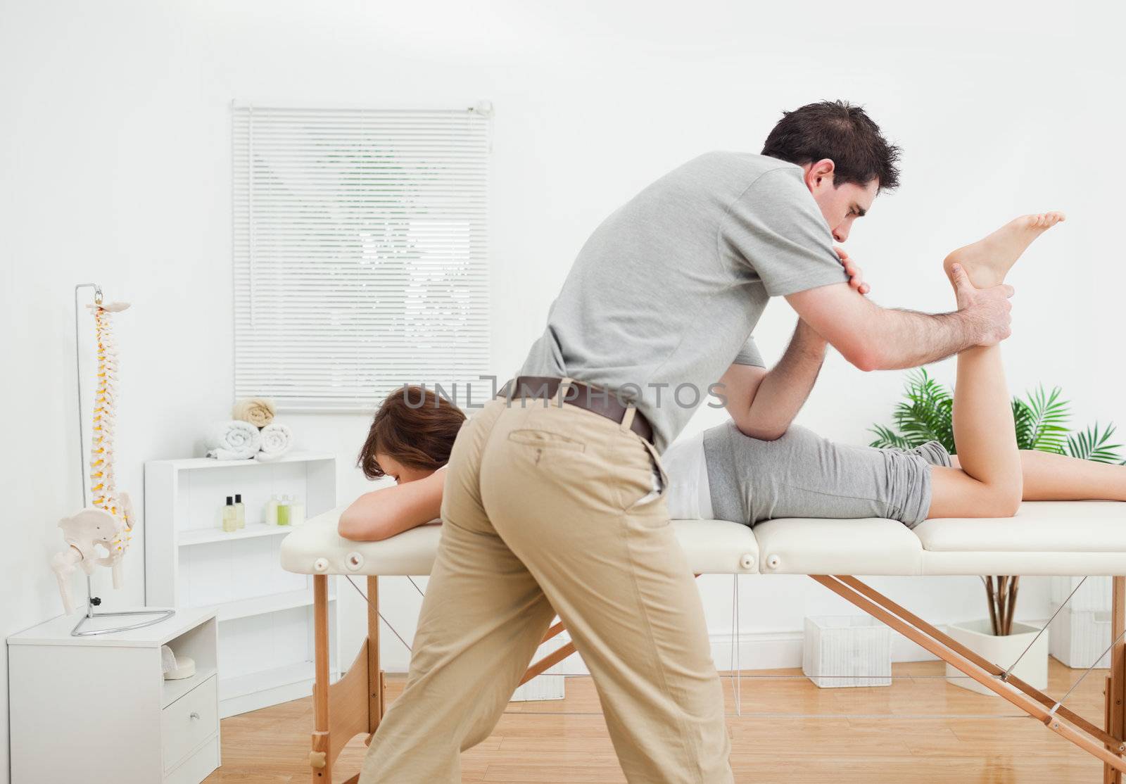 Brunette woman being stretched by a physiotherapist in a room