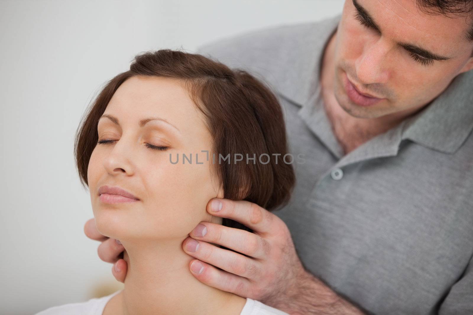 Physiotherapist massaging the neck of a patient in a room