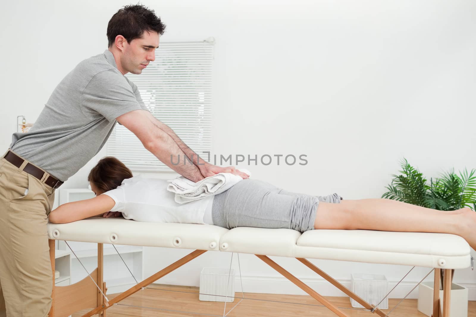 Woman lying while being massaged with a towel in a room