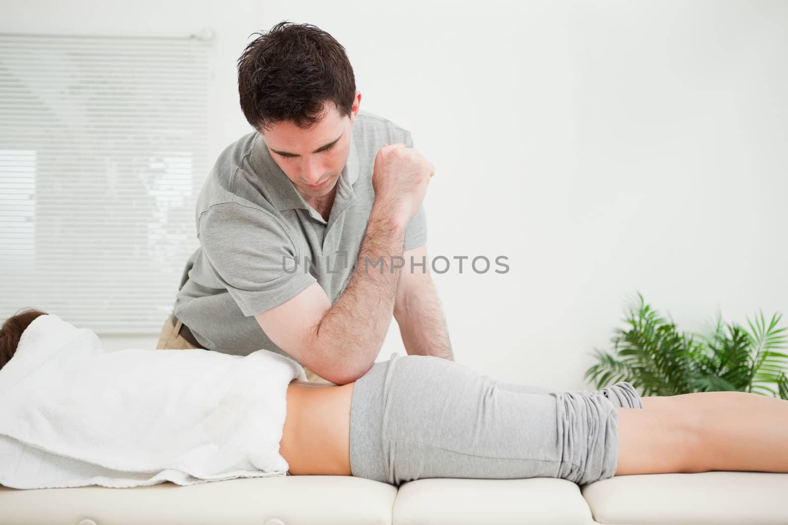Man pressing the back of a woman with his elbow in a room