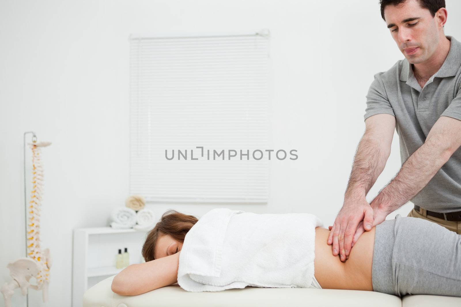 Masseur massaging the back of a brunette woman in a room