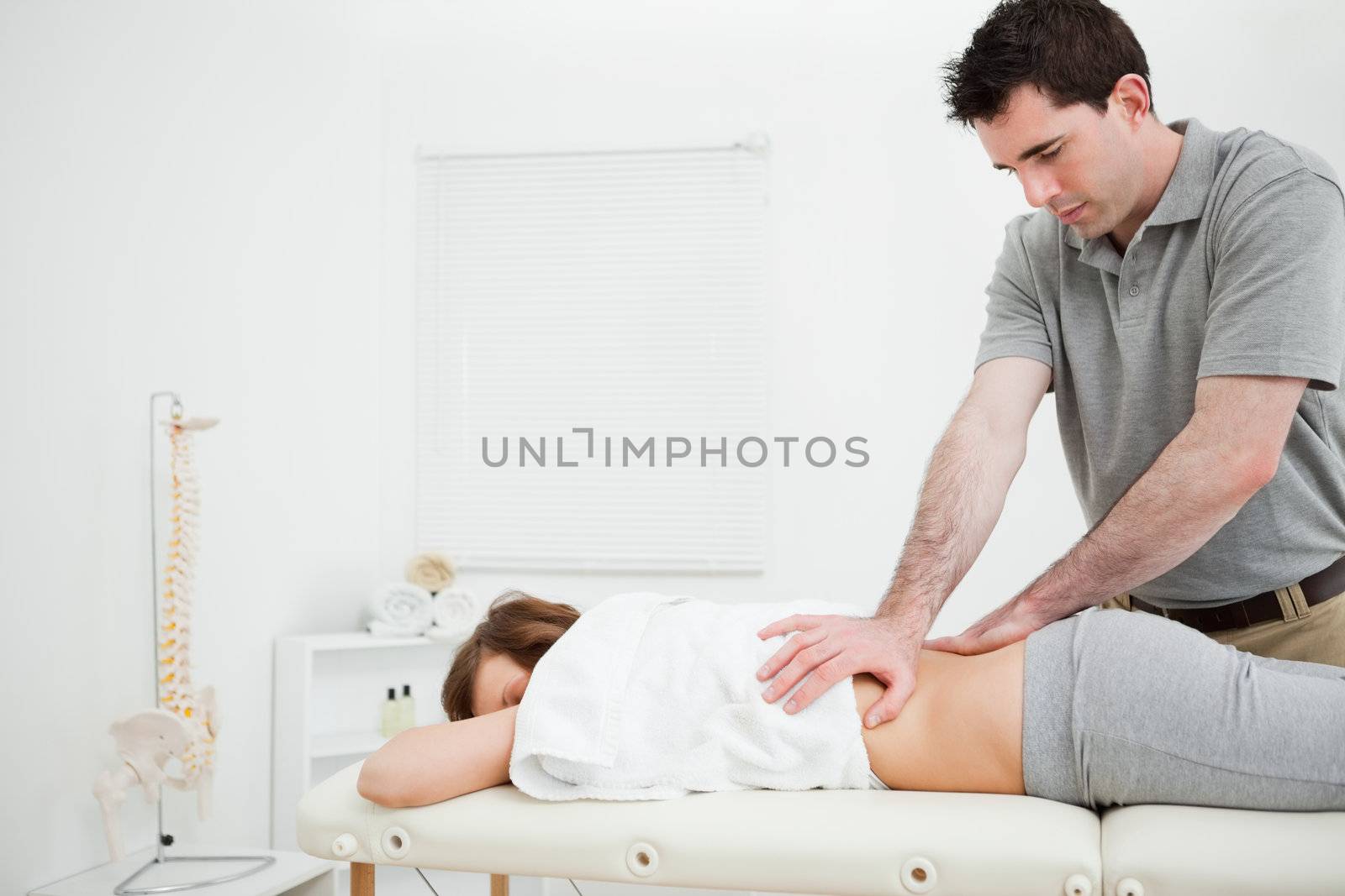 Serious practitioner massaging the lower back of a woman in a room