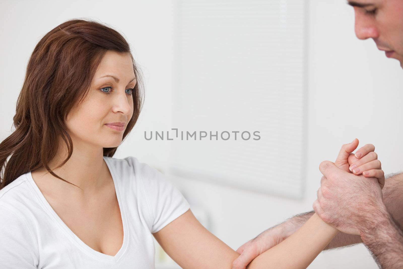 Woman sitting while a man examine her arm in a room
