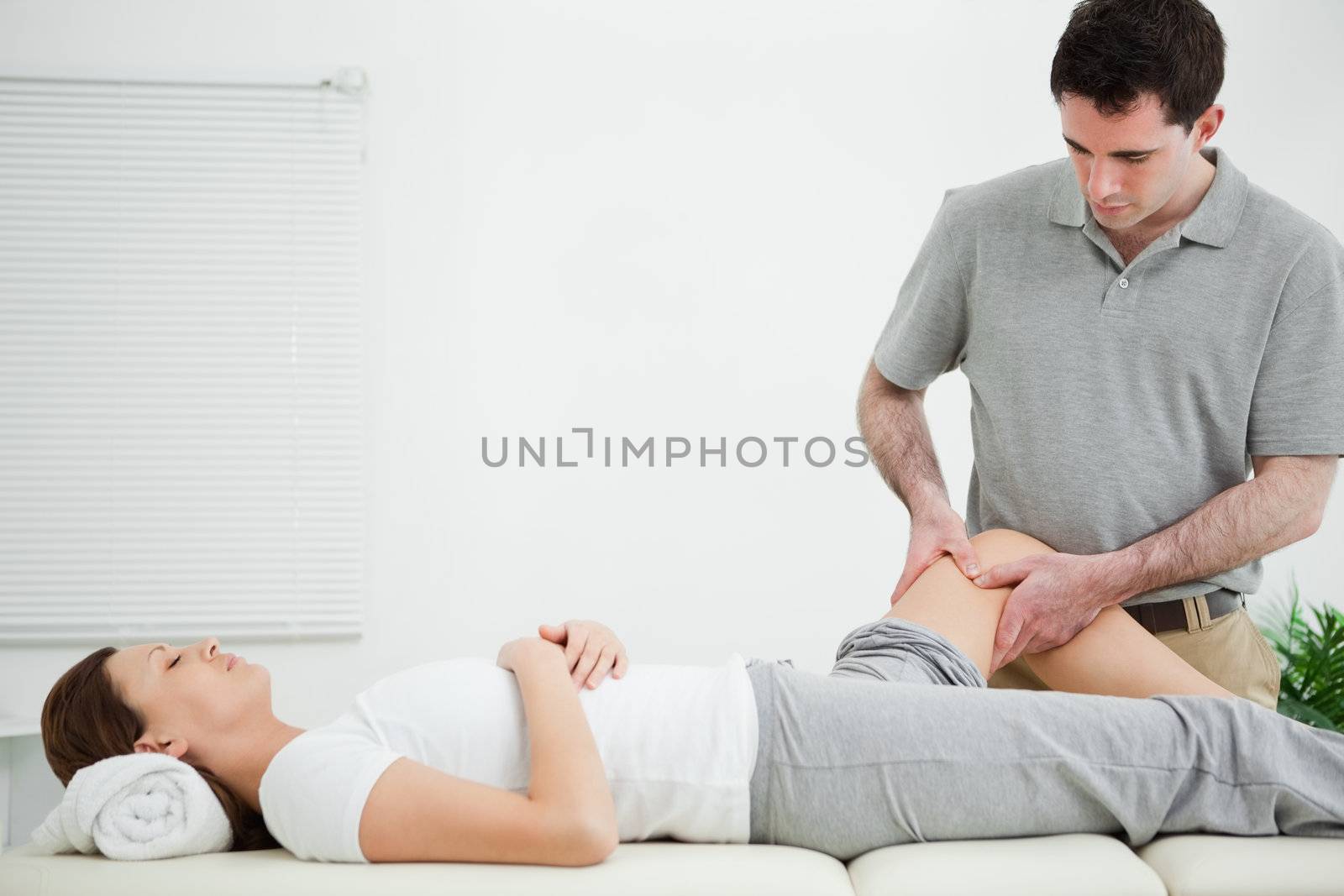 Physiotherapist massaging the leg of a woman while standing in a room