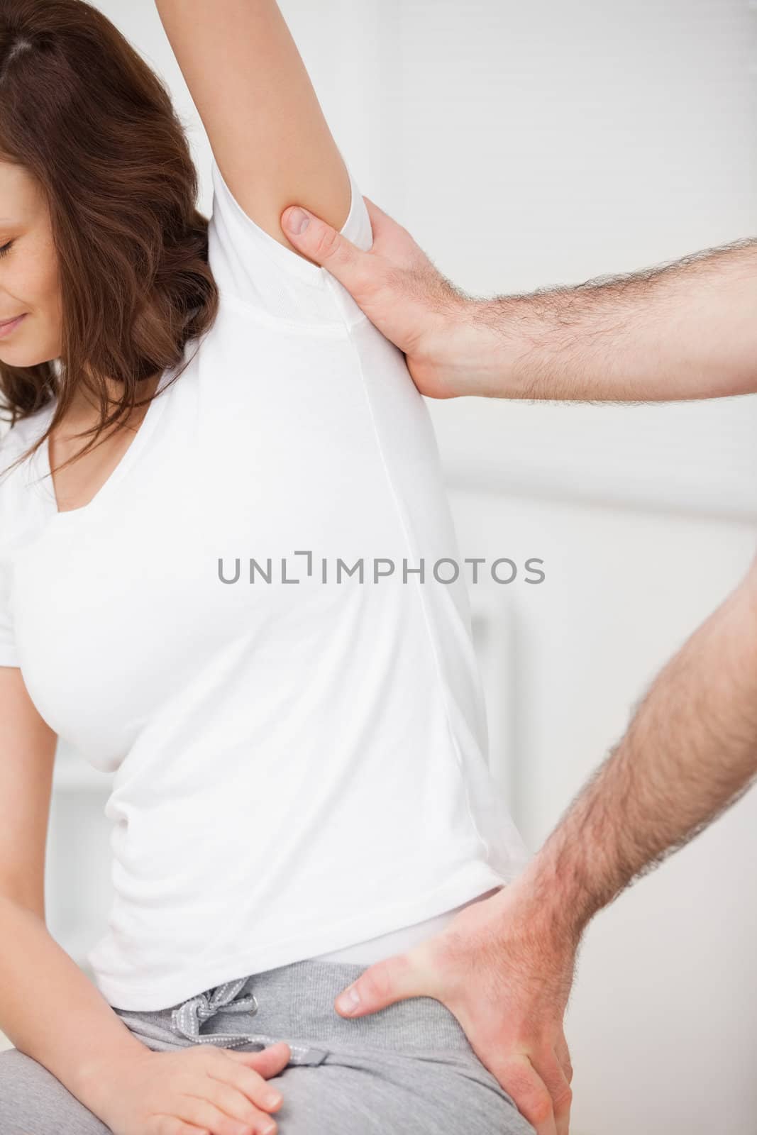 Close-up of a woman being stretched while sitting by Wavebreakmedia