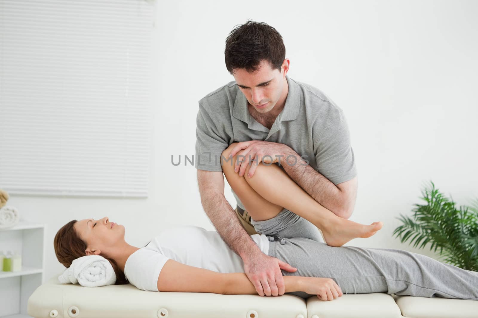 Brown-haired woman being stretched by a man in a room