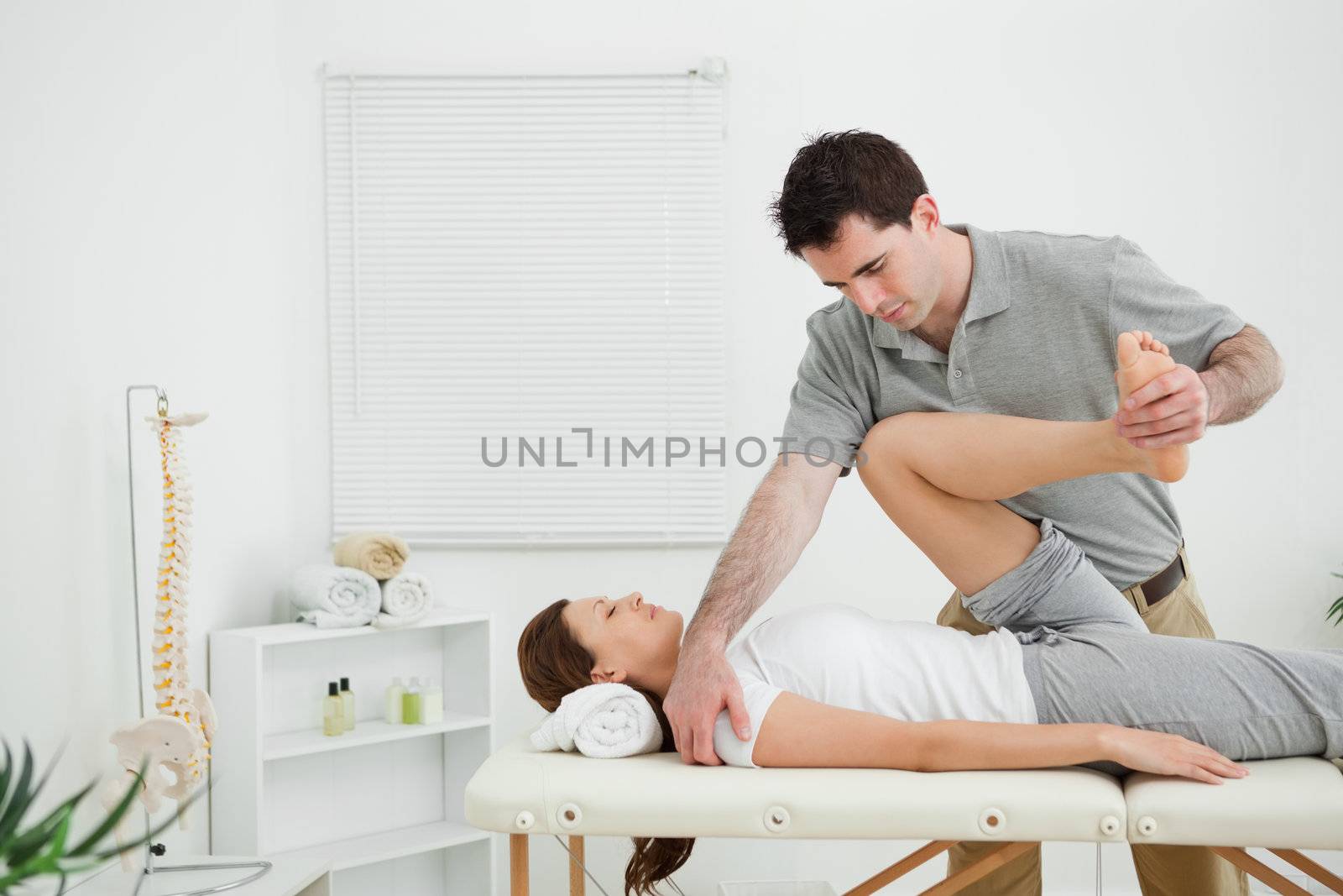 Brunette physiotherapist stretching a leg while standing in a room