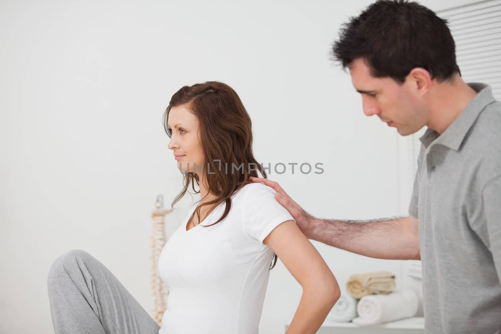 Woman sitting while a man is touching her back in a room