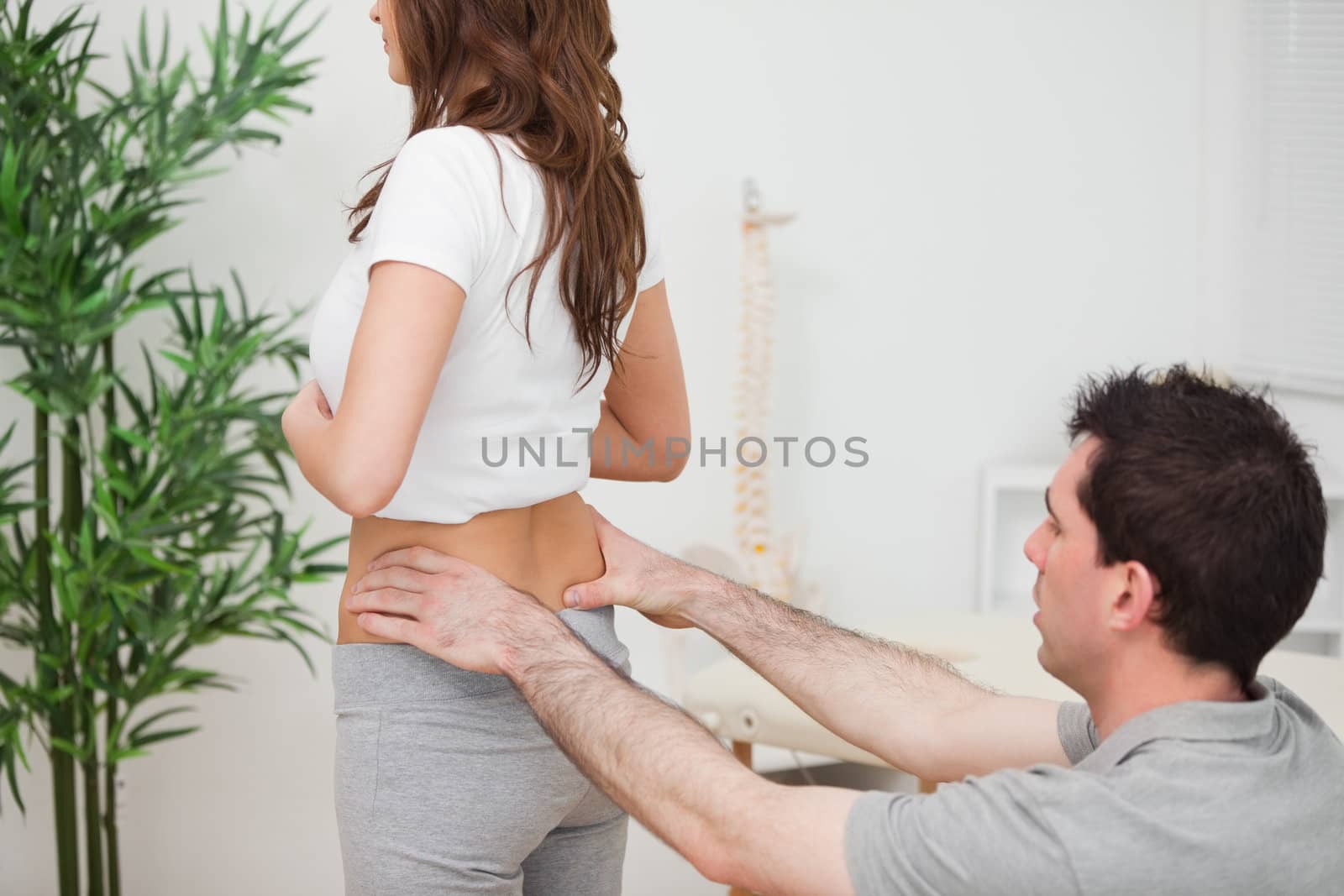 Doctor sitting while examining the hips of a woman in a room