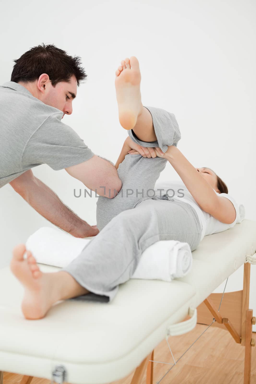 Brown-haired woman lying while stretching her leg in a room