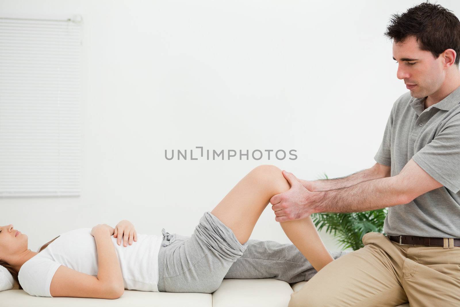 Physiotherapist sitting while massaging a knee in a room