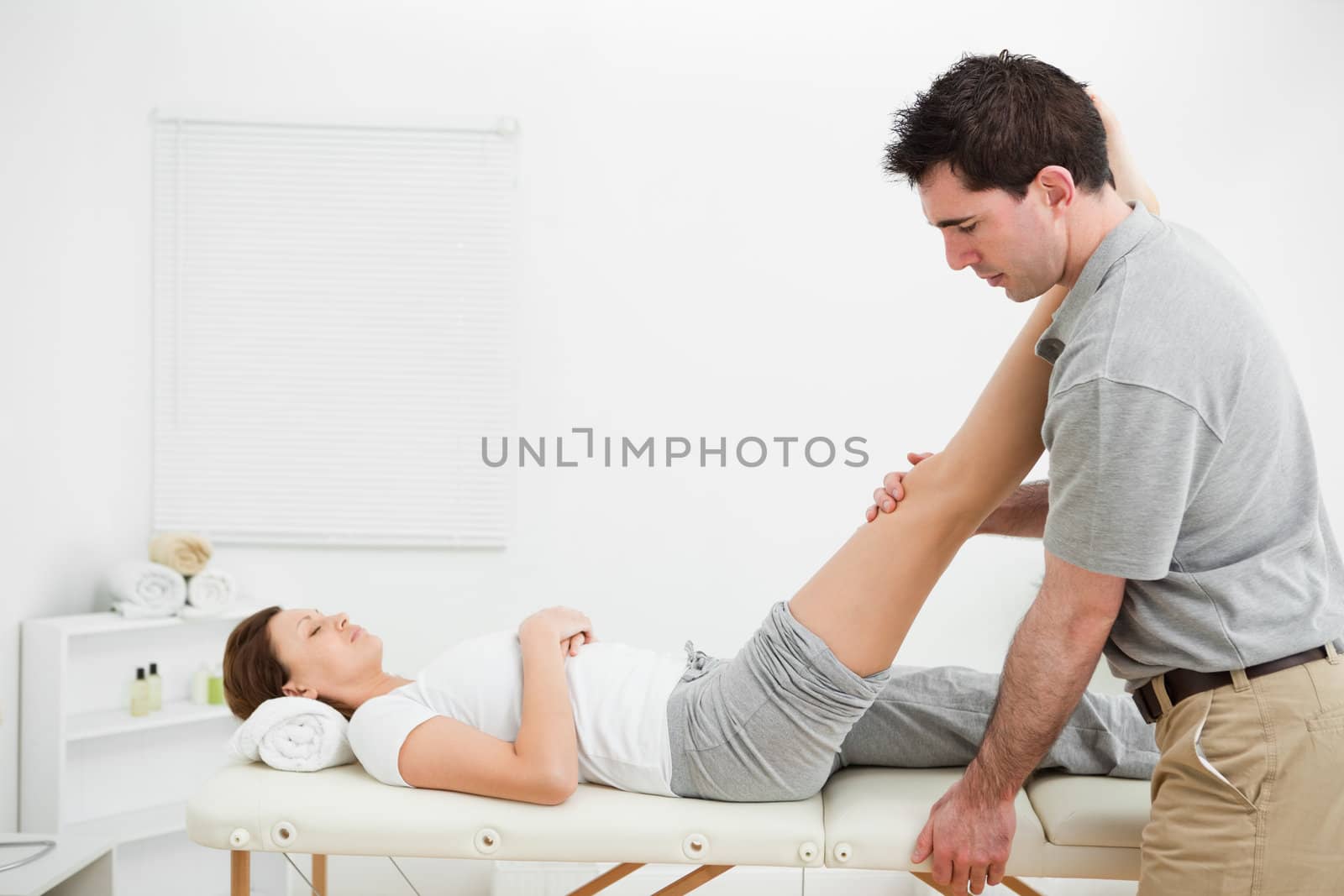 Man massaging a leg while placing it on his shoulder in a room