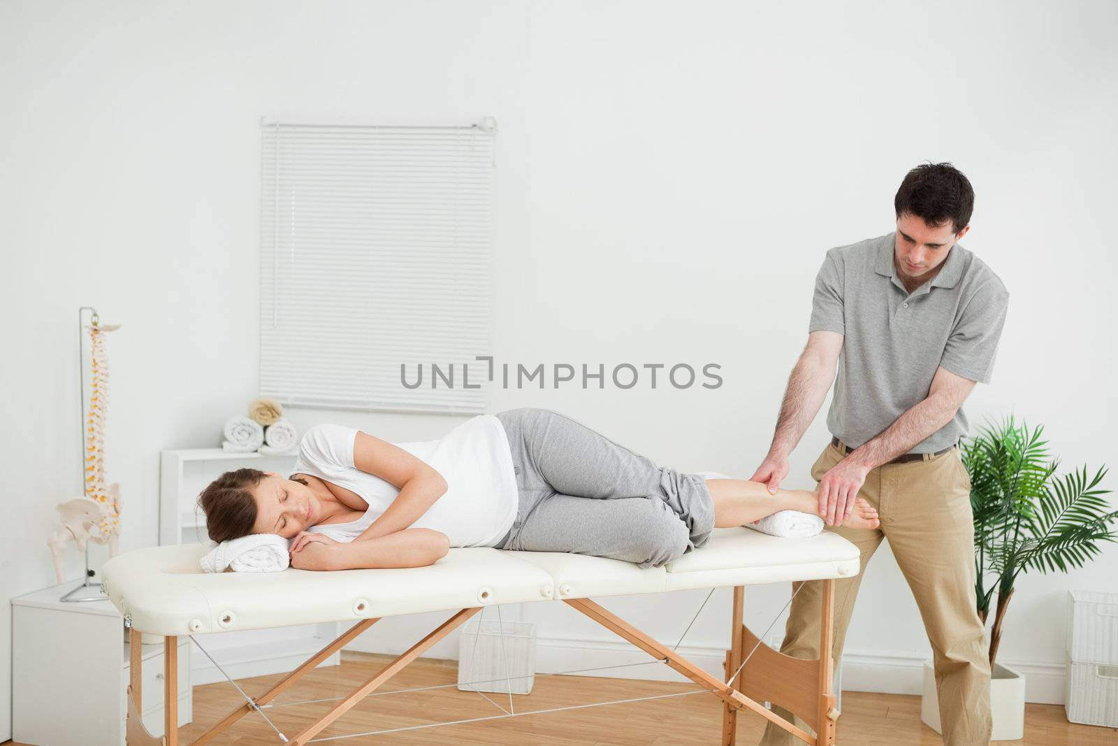 Woman lying on her side while being massaged by a man in a room