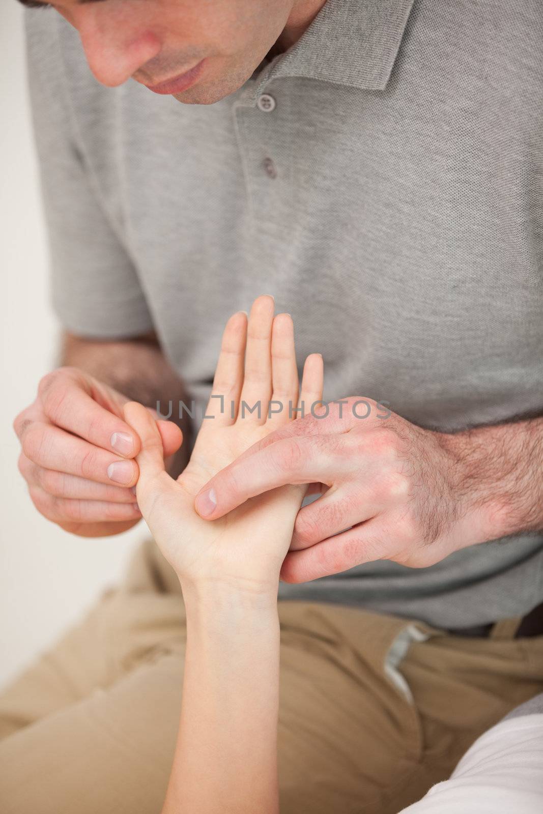 Man massaging the thumb of a woman in a room