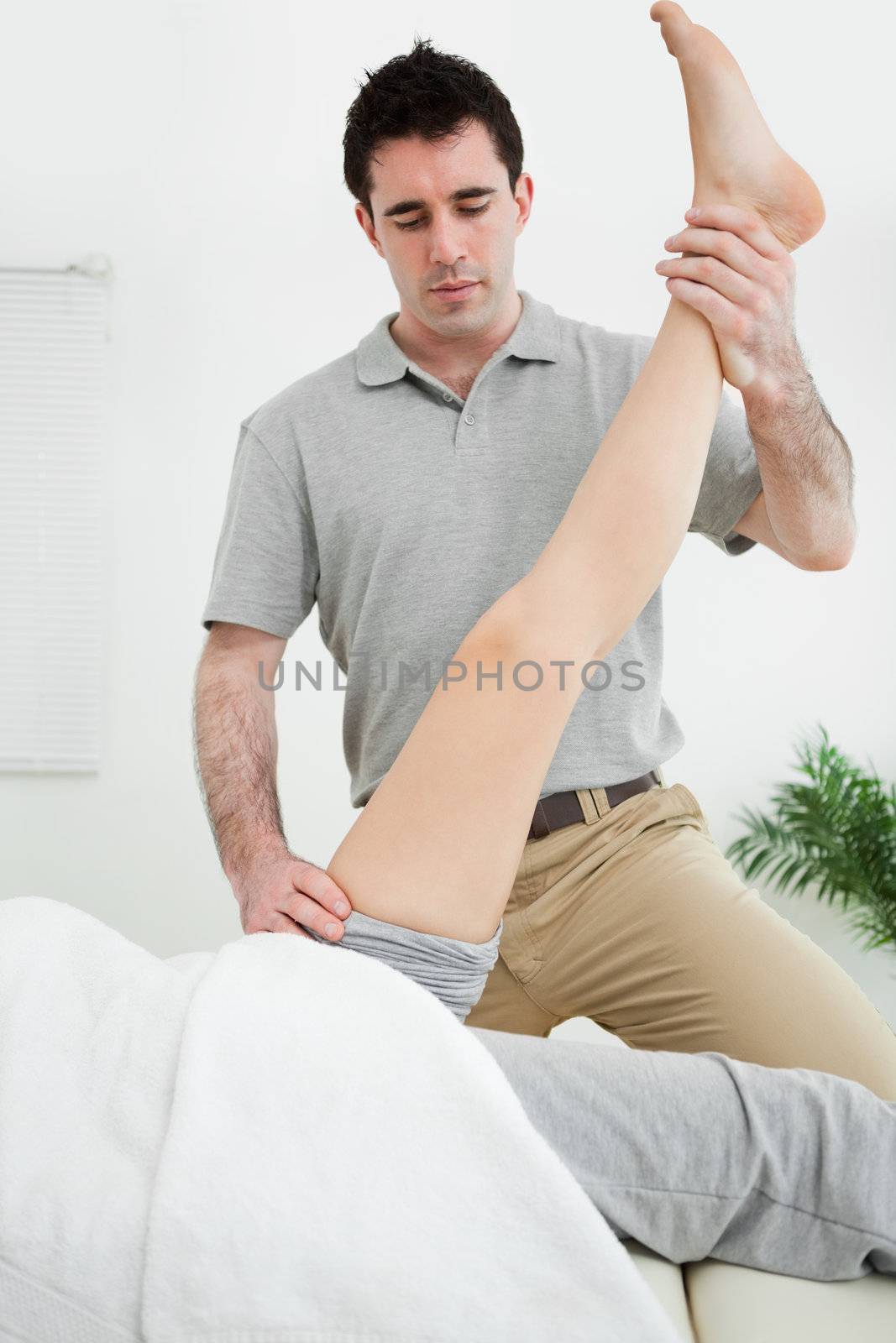 Physiotherapist raising the leg of a patient in a room