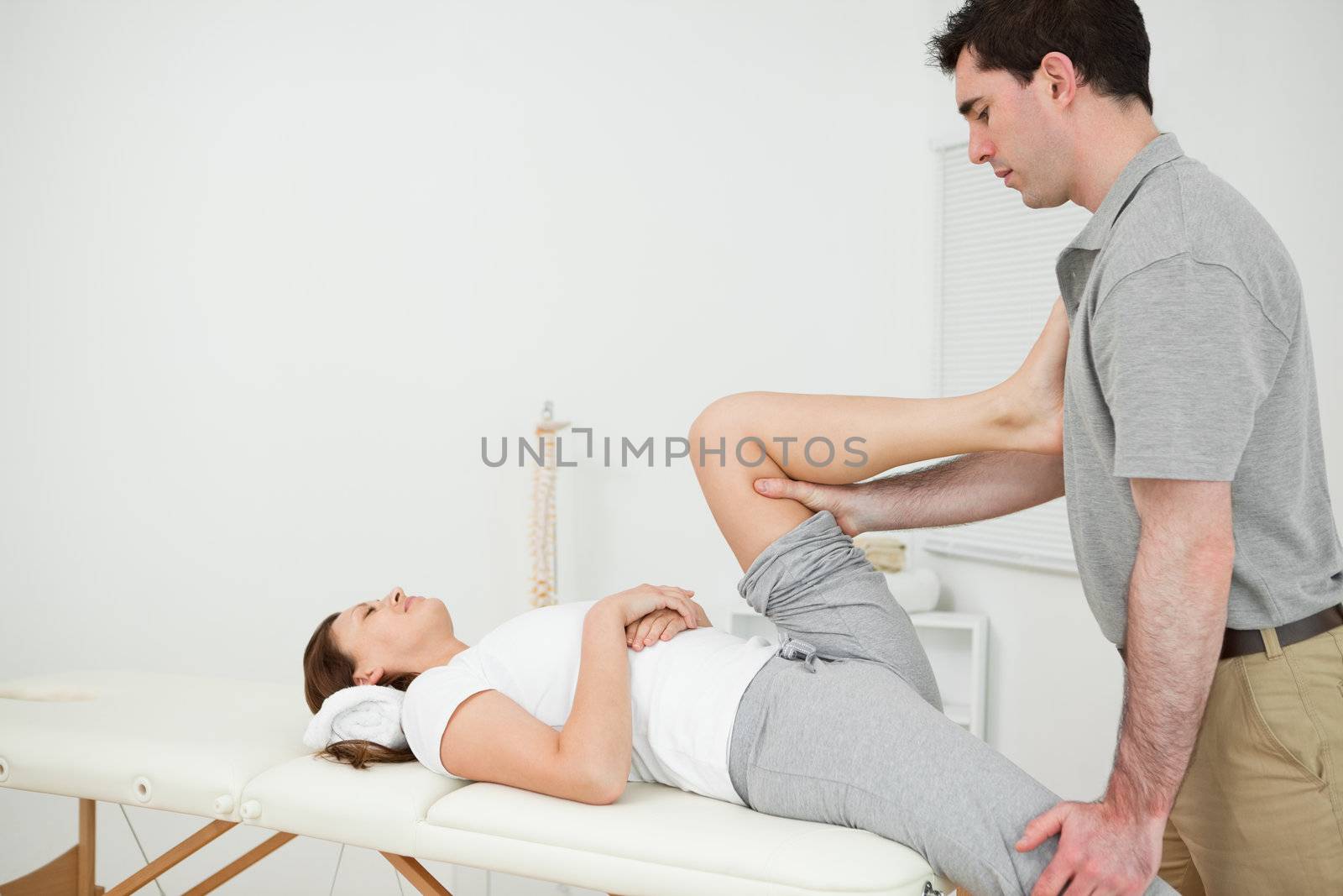 Osteopath stretching the leg of his patient in his medical room